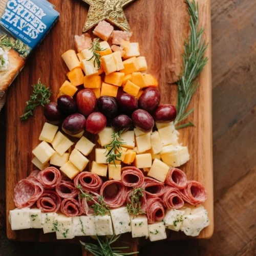 Christmas tree shaped charcuterie board adorned with festive treats.