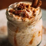 Bowl of cinnamon roll overnight oats topped with cinnamon and raisins