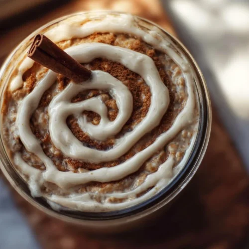 Bowl of cinnamon roll overnight oats topped with cinnamon and raisins.