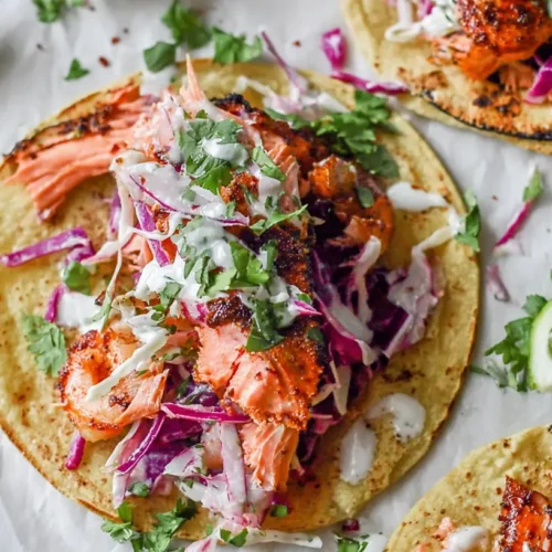 A plate of fresh salmon tacos garnished with lime and cilantro.