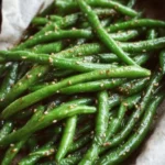 Plate of miso green beans garnished with sesame seeds and scallions