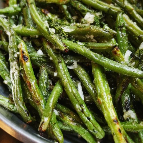 Oven-roasted green beans served on a plate with seasoning