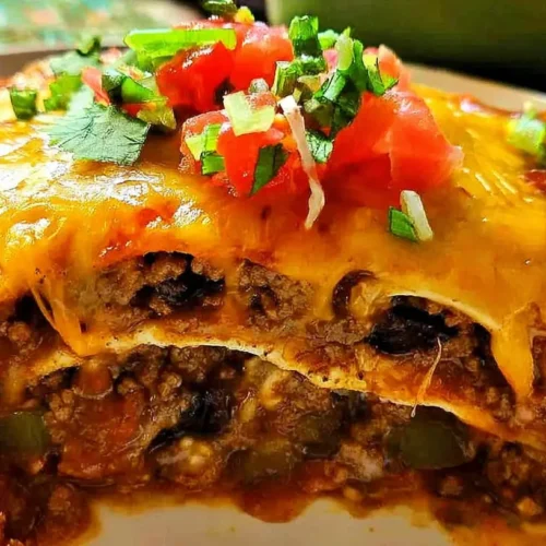 A bubbling enchilada casserole fresh from the oven, topped with melted cheese and herbs.