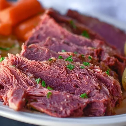 A slow cooker filled with tender corned beef, cabbage, carrots, and potatoes, ready to be served as a meal.