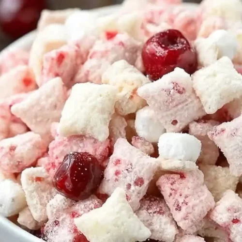A bowl of cherry cheesecake puppy chow, featuring a delightful blend of colors.