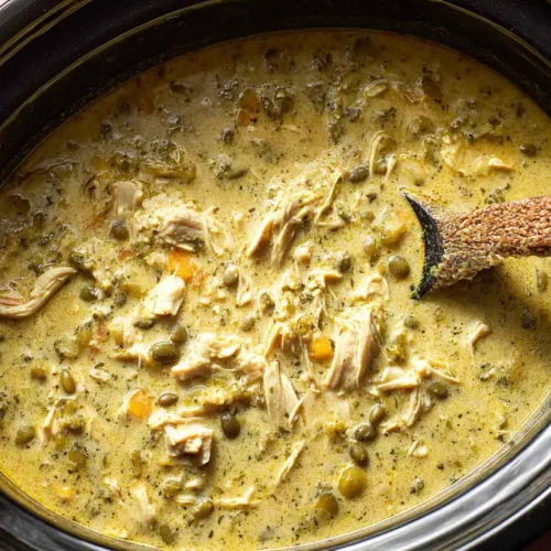 A steaming bowl of crock pot green enchilada chicken soup garnished with fresh cilantro and a dollop of sour cream.