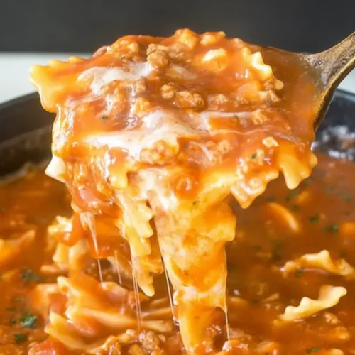 Close-up of a steaming bowl of hearty lasagna soup with ricotta and herbs.