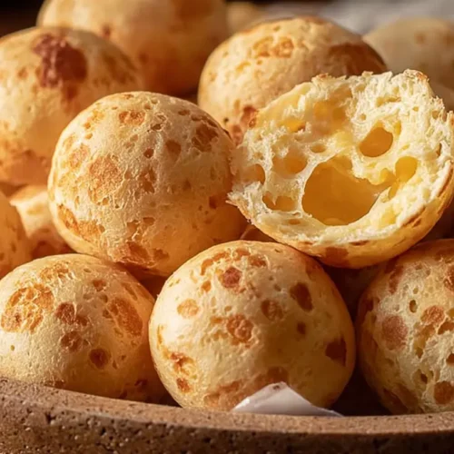 A plate full of golden brown pão de queijo, perfectly baked.