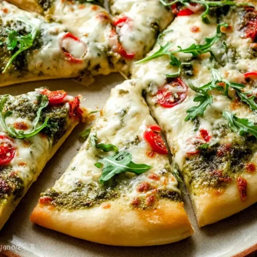 A freshly baked pesto pizza with vibrant green sauce and melted cheese.