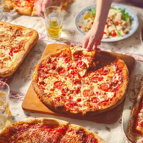 A cozy indoor setting with various pizzas laid out, suggesting a fun pizza night