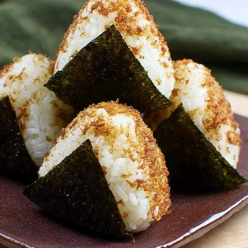 A close-up of savory chicken rice balls, perfectly spherical and golden brown.