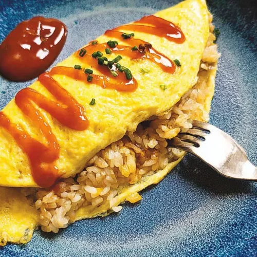 A freshly prepared omelette rice dish with a fluffy egg and savory sauce