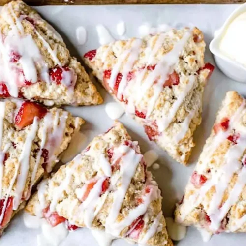 A basket of freshly baked strawberry scones on a wooden table.