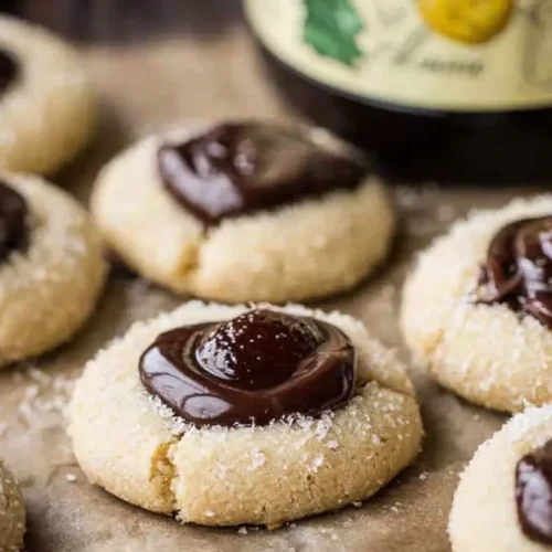 A close-up of multiple chocolate thumbprint cookies with a rich chocolate filling.