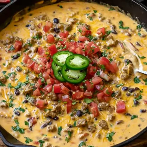 A bubbling skillet of savory Cowboy Queso, ready to be served hot.