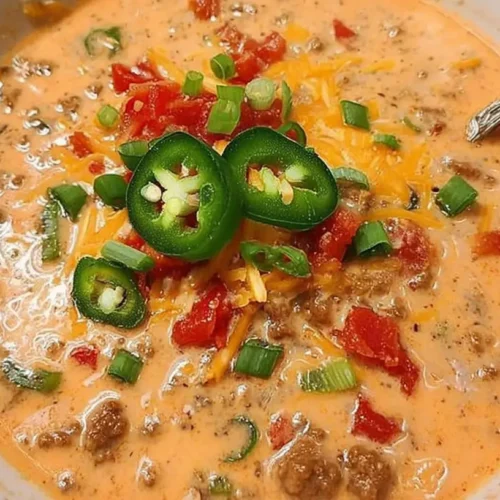 A bowl of creamy cheesy ground beef taco soup topped with sour cream and cilantro