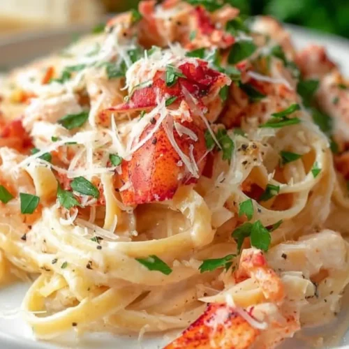 A serving of creamy lobster alfredo pasta with generous pieces of lobster meat
