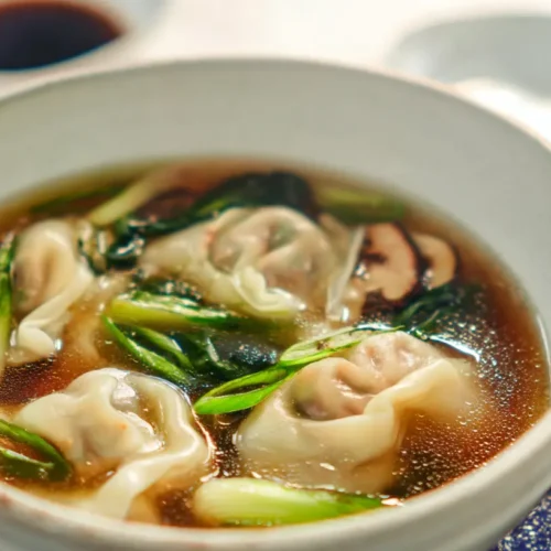 A steaming bowl of gyoza soup with vegetables