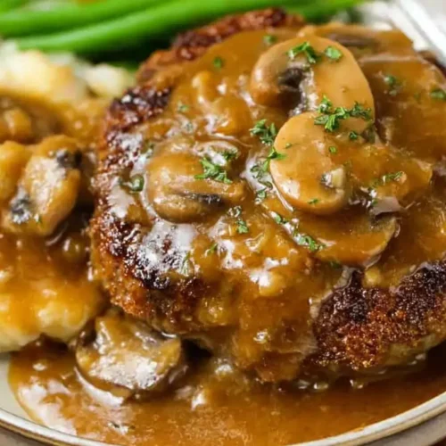 A serving of Salisbury steak and gravy with a side dish.