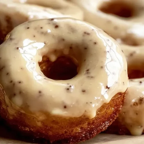 Freshly baked maple glazed donuts arranged on a cooling rack.