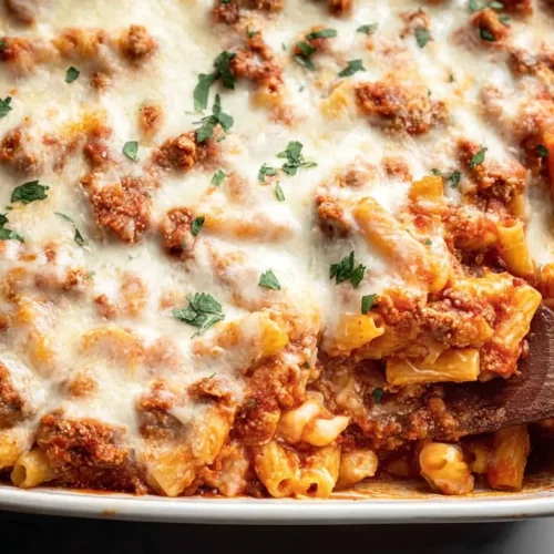 A steaming dish of baked ziti pasta dinner, rich with cheese and sauce.