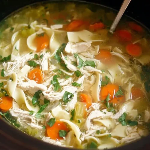 A comforting bowl of crockpot chicken noodle soup, steaming and ready to eat.