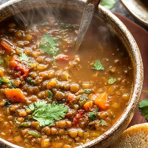 A comforting bowl of Crockpot lentil soup garnished with fresh herbs