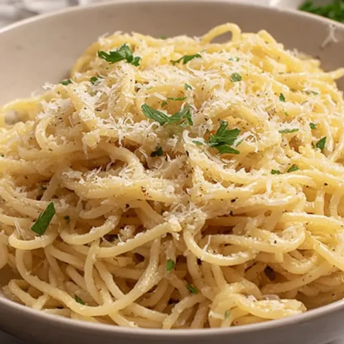 A close-up of a bowl of garlic butter pasta dinner, garnished with fresh herbs.