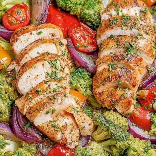 A variety of vegetables and protein cooking on a large one-pan, for a healthy dinner recipe.