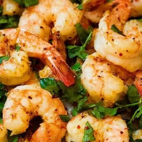 A vibrant clean eating shrimp recipe artfully arranged on a plate with fresh vegetables.