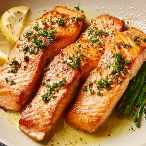A perfectly cooked pan seared salmon fillet on a white plate.