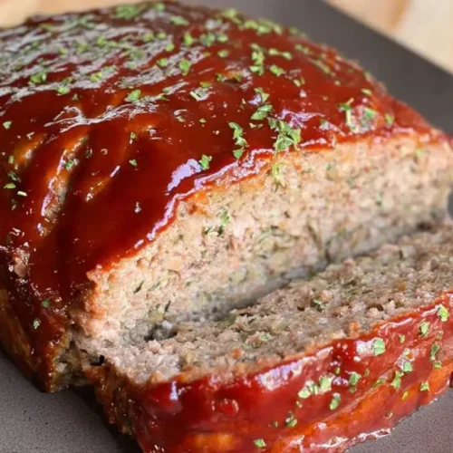 A serving of lightened-up classic meatloaf on a white plate, garnished.