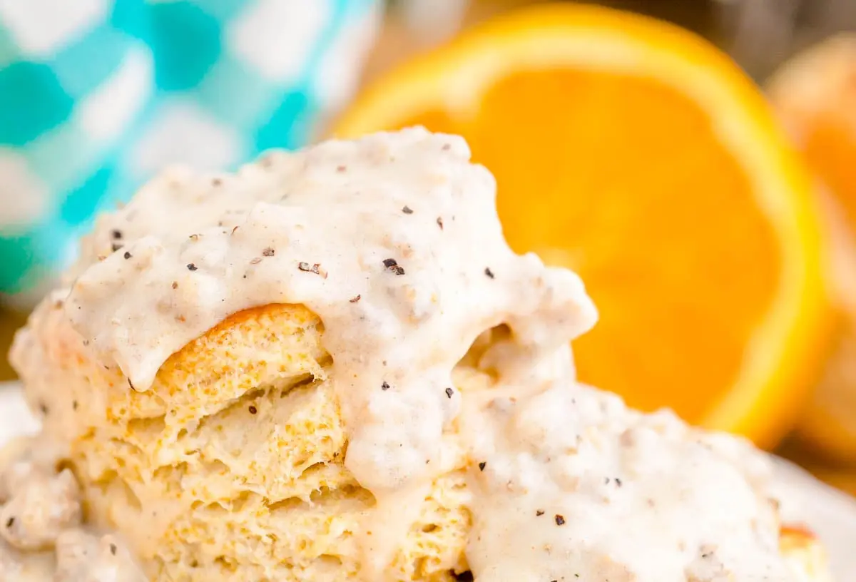 Fluffy biscuits drenched in creamy sausage gravy on a white plate