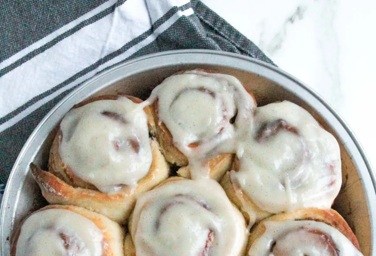 Freshly baked cinnamon rolls generously topped with white cream cheese frosting.