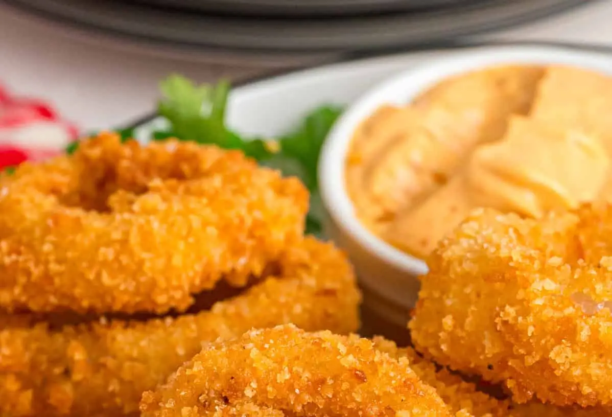A pile of crispy, golden-brown onion rings, freshly fried.