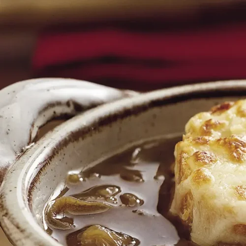 A bowl of crockpot French onion soup with melty cheese and croutons