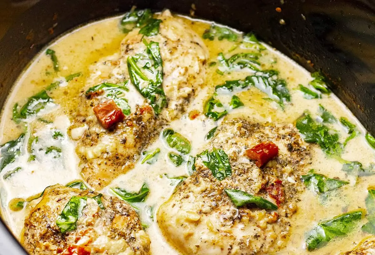 A creamy crockpot Tuscan chicken dish, rich with vibrant colors and herbs, ready to serve.