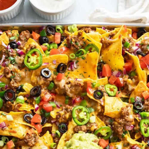 A vibrant plate of loaded nachos with melted cheese, jalapeños, and salsa.