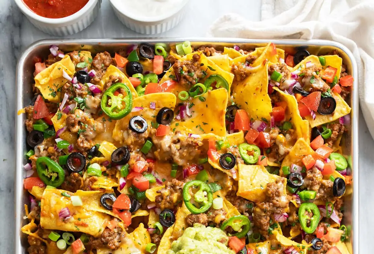 A vibrant plate of loaded nachos with melted cheese, jalapeños, and salsa.
