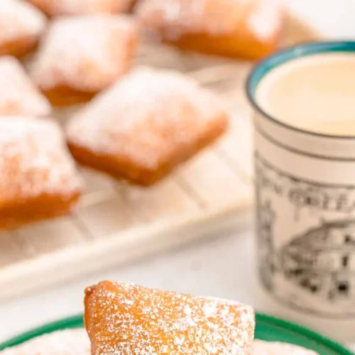 Freshly made New Orleans beignets dusted generously with powdered sugar in a classic setting.