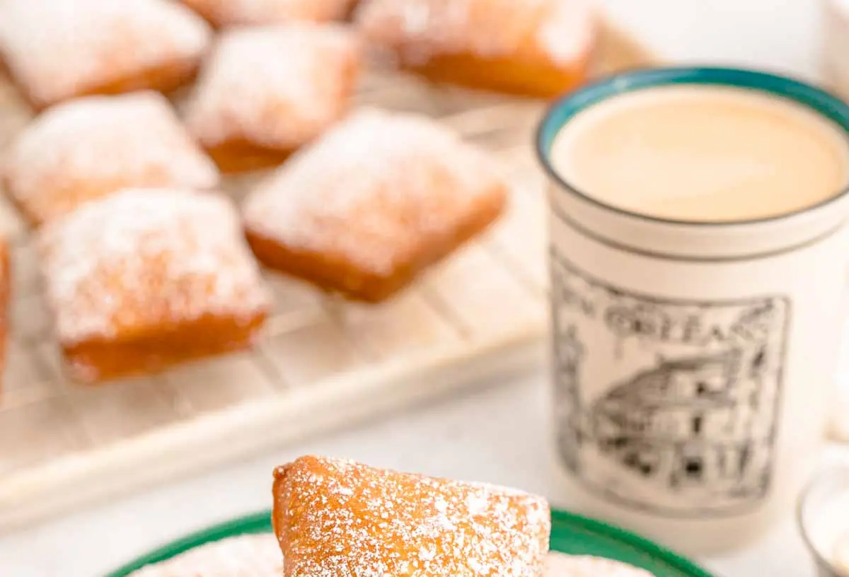 Freshly made New Orleans beignets dusted generously with powdered sugar in a classic setting.