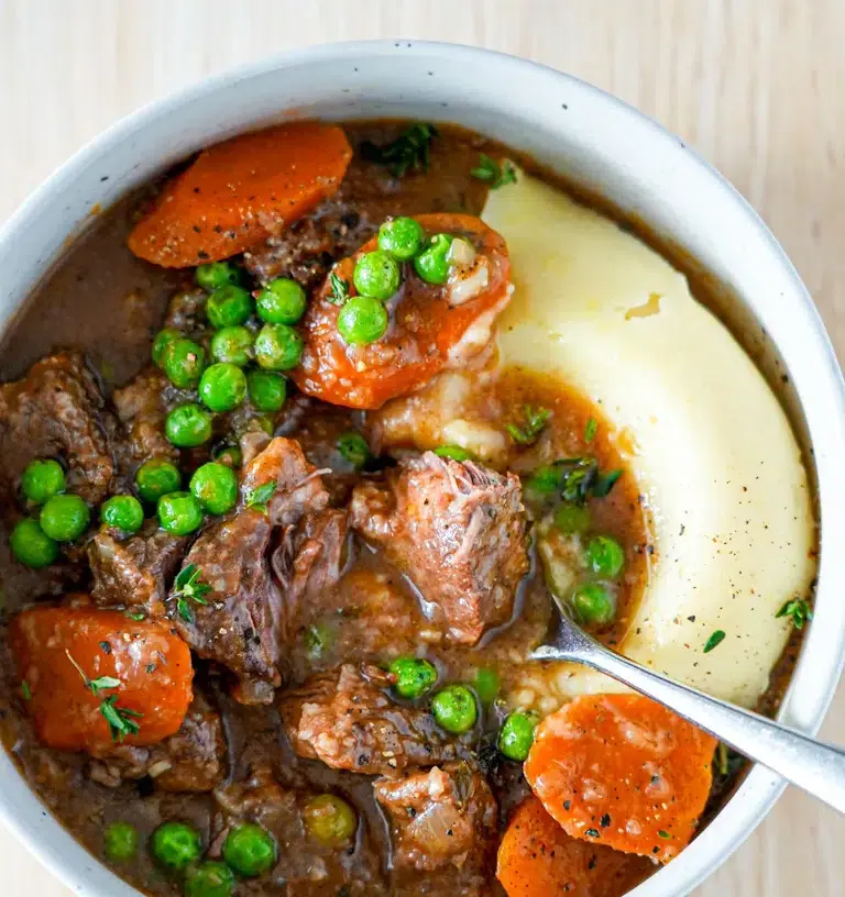 A steaming bowl of slow cooker beef stew garnished with fresh parsley.