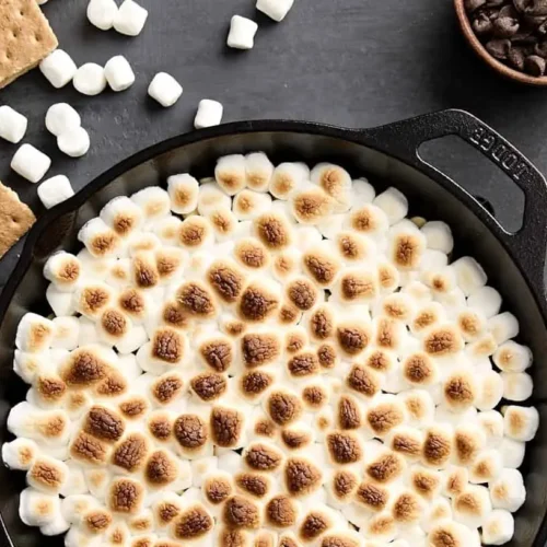 A bubbling s'mores dip with toasted marshmallows on top, ready for dipping