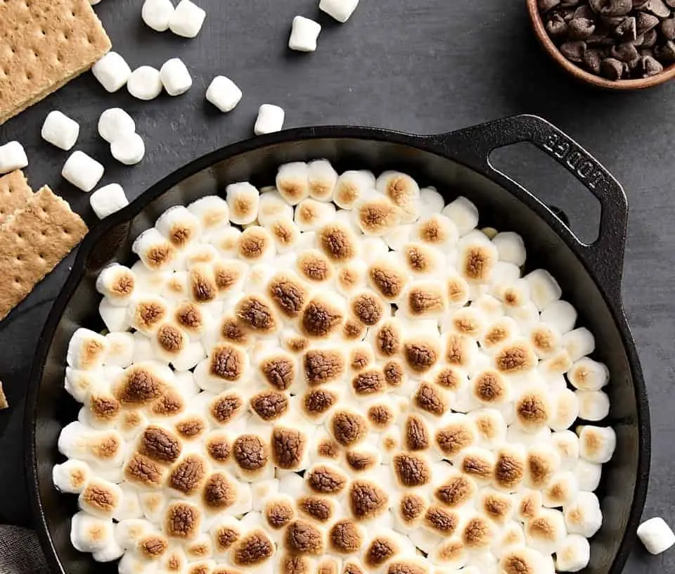 A bubbling s'mores dip with toasted marshmallows on top, ready for dipping