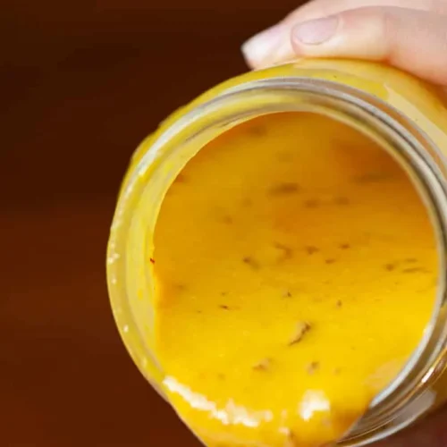 A jar of South Carolina mustard BBQ sauce with a golden hue.