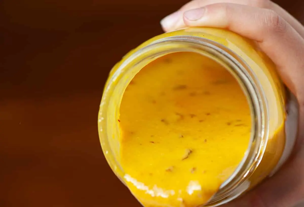 A jar of South Carolina mustard BBQ sauce with a golden hue.